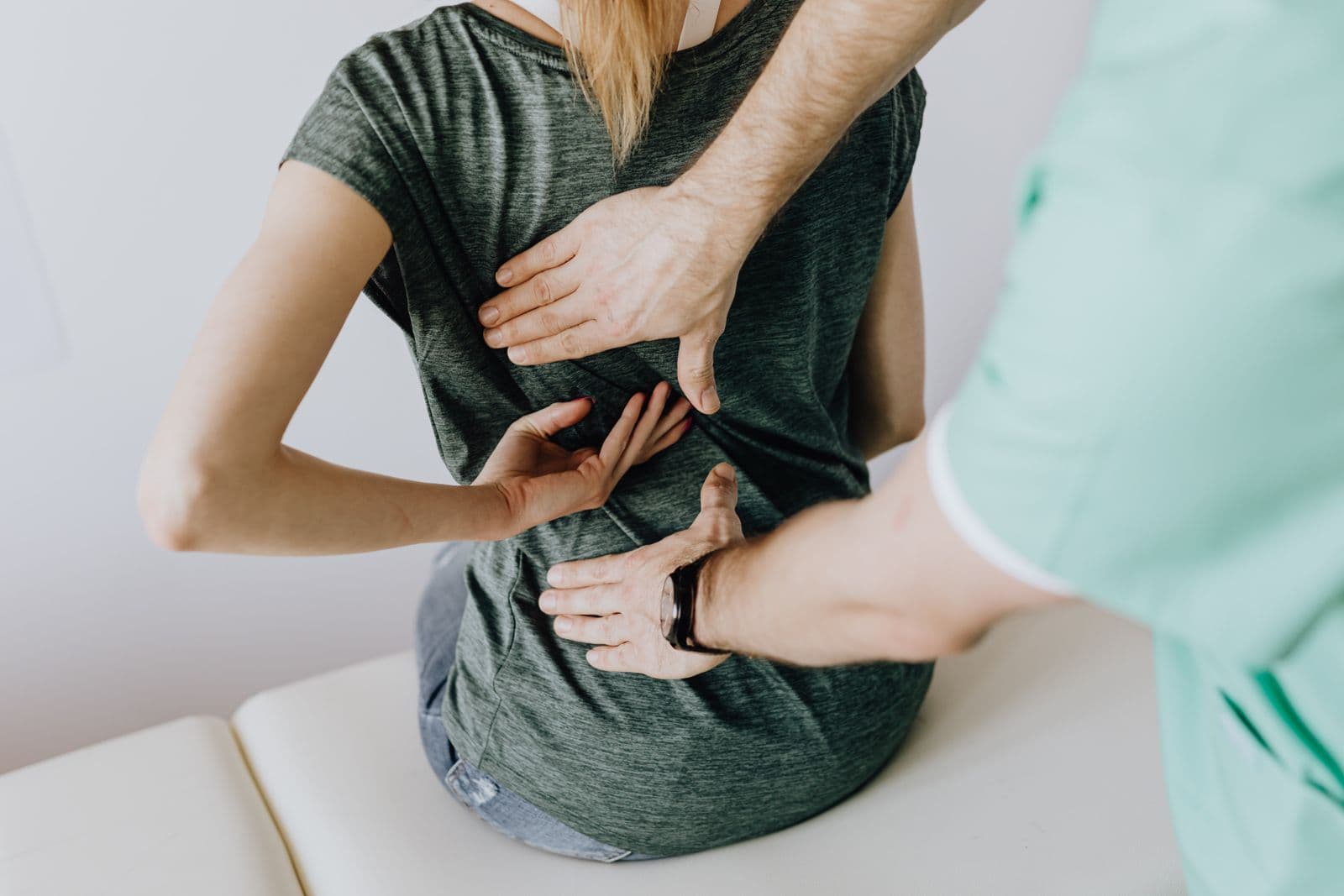 Chiropractor examining a patient's back for preventative spinal care and wellness, Forest Hills Queens NY