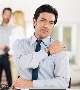 Portrait of a businessman at work suffering from shoulder pain. Portrait of stressed man holding shoulder and stretching after work. Mature business man tired and stressed after working for long.